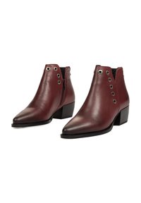 Botas de tobillo de cuero burdeos con punta afilada, suela negra contrastante, cremallera lateral y ojales de metal en el exterior.