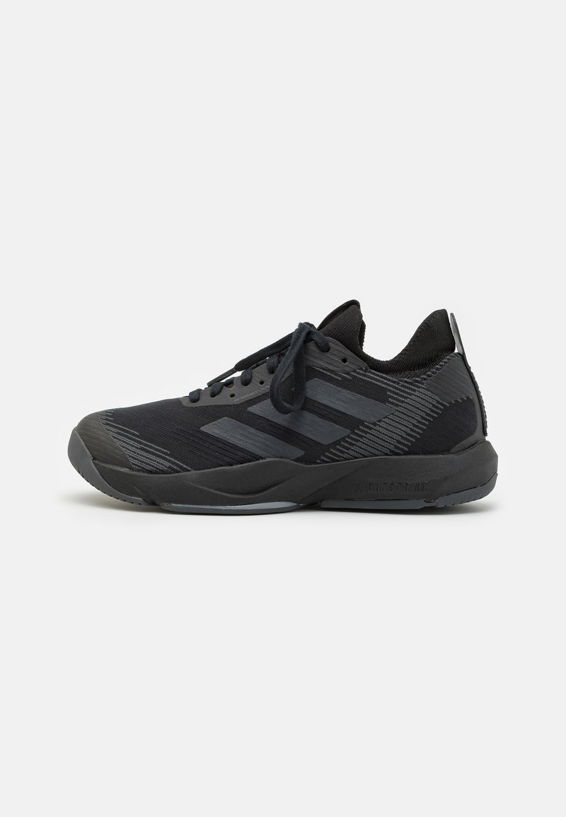 Scarpa sportiva nera con lacci, tomaia in maglia, colletto imbottito e suola spessa, caratterizzata da tre strisce scure di lato e dettagli testurizzati.