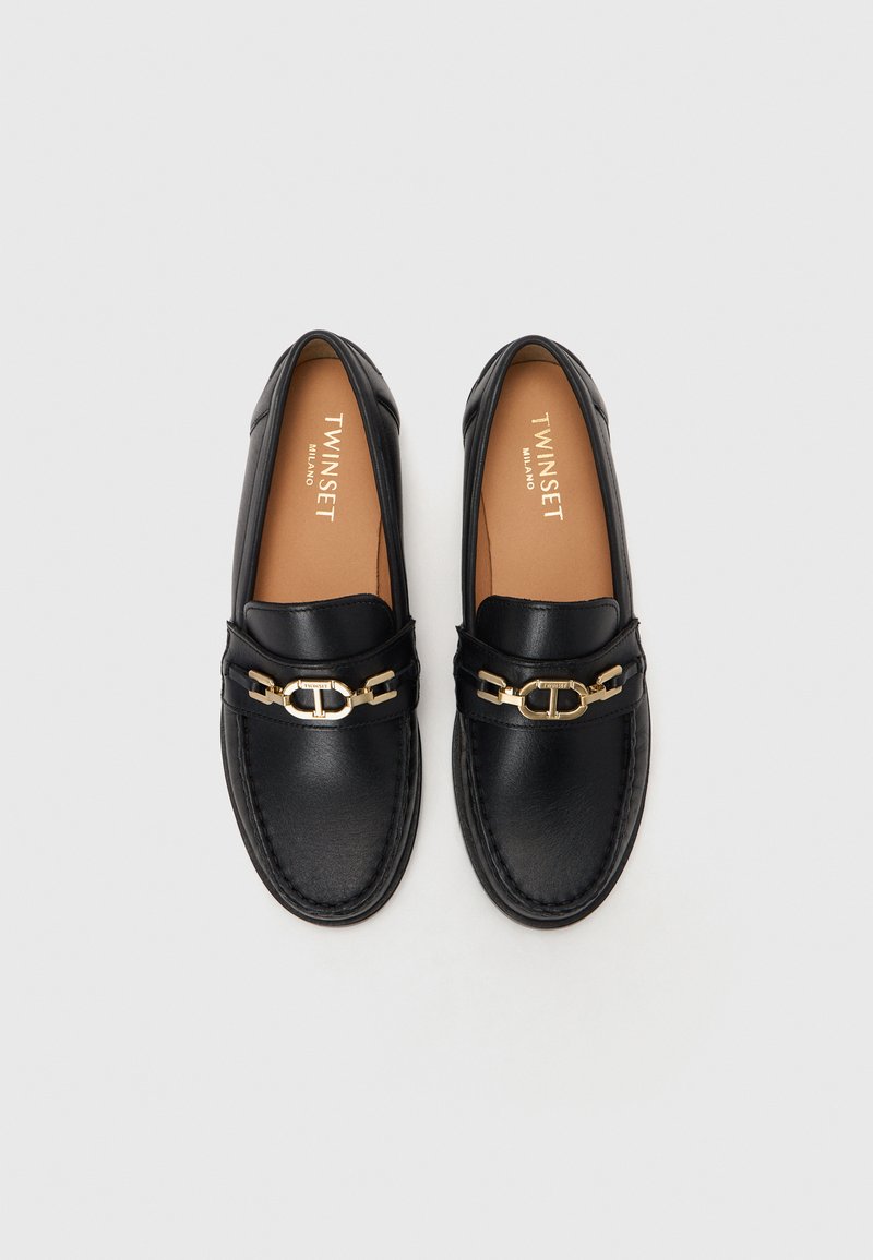 Czarne skórzane loafersy z złotymi detalami z przodu, kontrastowym przeszyciem i gładką teksturą. Nazwa marki "TWINSET" widoczna wewnątrz.