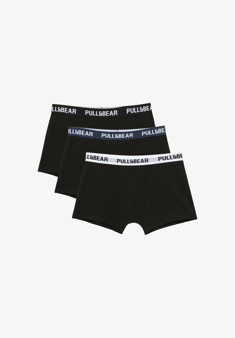 Trois boxers noirs pour hommes avec des ceintures élastiques de marque en noir, bleu et blanc empilés en rang.