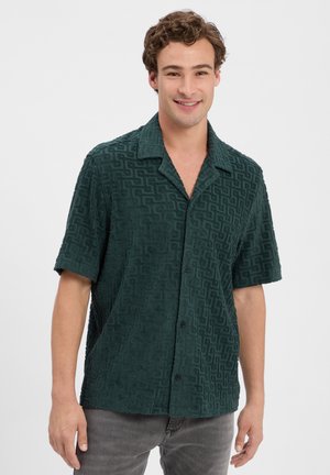 Chemise à manches courtes, boutonnée, en tissu vert foncé avec un motif géométrique texturé, dotée d'un col et d'une coupe décontractée.
