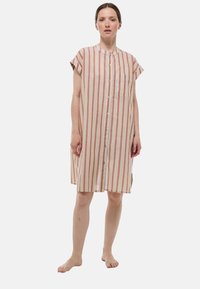 Robe chemise rayée en crème, rose et jaune. Caractéristiques : manches courtes, col mandarin, boutons sur le devant et poche poitrine. Tissu doux.