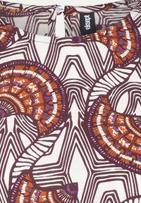 Tissu à motifs présentant des designs circulaires audacieux en orange et violet, entrecoupés de lignes blanches et marron sur un fond clair.