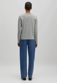 Grijze long-sleeve t-shirt met een ronde hals, gecombineerd met hoge blauwe jeans met een rechte pasvorm en subtiele achterzakken.