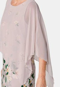 Helle rosa, fließende Bluse mit langen, geschichteten Ärmeln; florales Muster in sanften Farben am Saum; glattes Material, runder Ausschnitt.