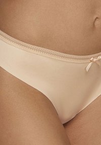 Mutandine bikini beige realizzate in un tessuto morbido, con un delicato bordo in pizzo e un piccolo fiocco decorativo sul davanti.