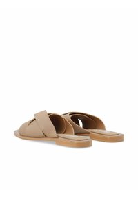 Sandali in pelle beige a infradito con strap incrociati, suole piatte e dettagli minimi. Il design presenta una texture liscia e lati aperti.