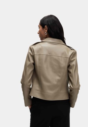 Veste en similicuir beige avec une silhouette ajustée, un col à revers et des détails cousus. Comprend des épaulettes aux épaules et une texture lisse.