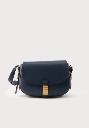 Bolso bandolera de cuero azul marino con herrajes dorados, tapa plegada y detalle de cierre decorativo. Cuenta con una correa ajustable y una textura suave.