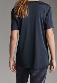 Black short-sleeve T-shirt with a smooth, shiny texture, round neck, and a slightly elongated back hem, displayed from the rear view.