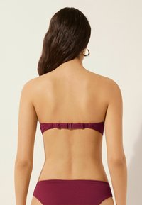 Bikini haut bandeau bordeaux avec fermoir réglable à l'arrière et bas taille haute assorti, présentant un tissu texturé. Vue arrière montrée.
