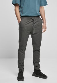 Pantalones gris ajustados con cintura elástica y cordón. Hechos de una tela texturada, cuentan con bolsillos laterales y un diseño de corte slim.