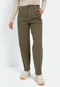 Olijfgroene katoenen broeken met een rechte pijp, voorkantzakken en een ritssluiting. Draag ze met lichtgekleurde sneakers en een beige top.