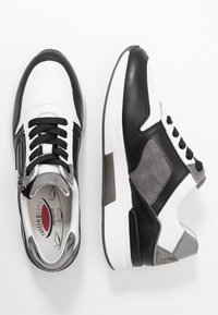 Svarta och vita sneakers med en blandning av läder och mocka. Har dragkedjestängning, texturerade accenter och en tjock vit sula.