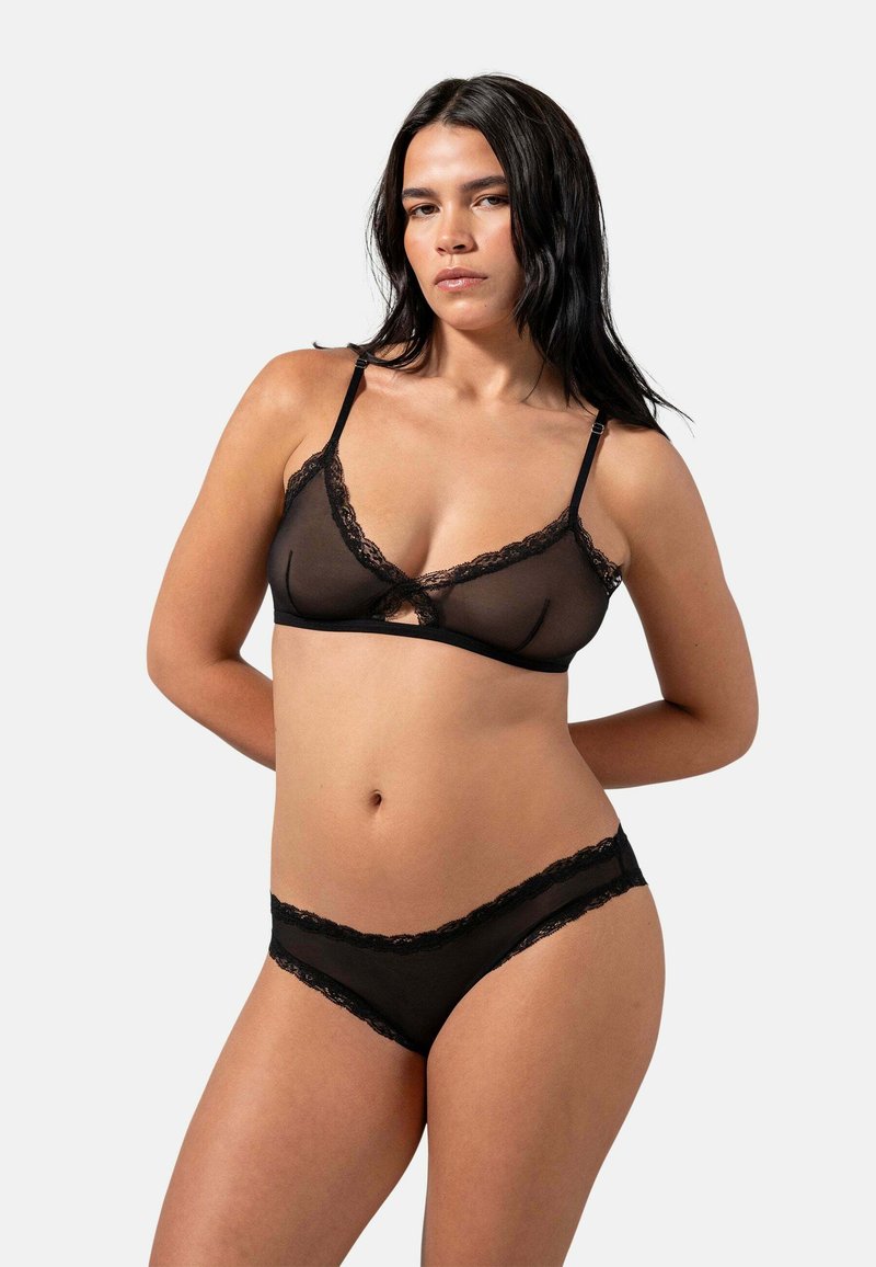 Set di lingerie nera composto da un reggiseno trasparente con rifiniture in pizzo e mutandine trasparenti abbinate con dettagli in pizzo, entrambe con spalline regolabili.