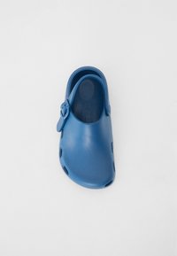 Blå plasttoffla med baksnörning, stora ventilationshål på sidorna och en slät, rundad design. Mönstrad sula.