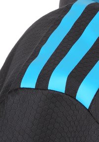 Tissu sportif noir avec un motif texturé, orné de trois bandes bleues horizontales au niveau de l'épaule pour un contraste et un intérêt visuel.