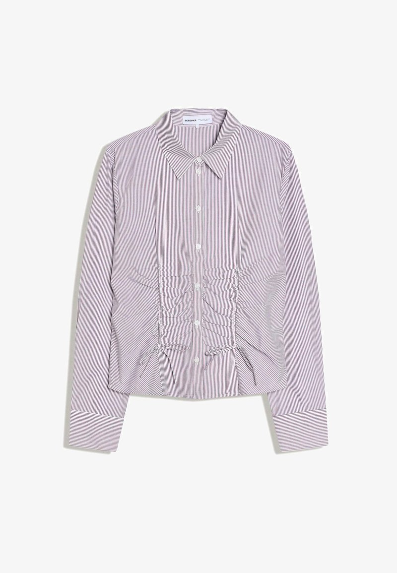 Chemise à manches longues rayée rouge et blanche avec col, détails froncés à l'avant et fermeture par boutons. Tissu doux avec une coupe structurée.
