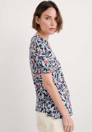 Top con stampa floreale a fondo navy, con maniche corte puff, fiori rossi e bianchi, vestibilità comoda e spacchi laterali per facilitare i movimenti.