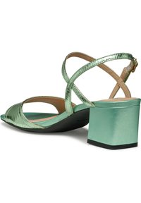 Sandalias verdes menta con tiras y un acabado brillante de charol, con punta abierta y tacón cuadrado. Presentan tiras cruzadas y una plantilla acolchada.