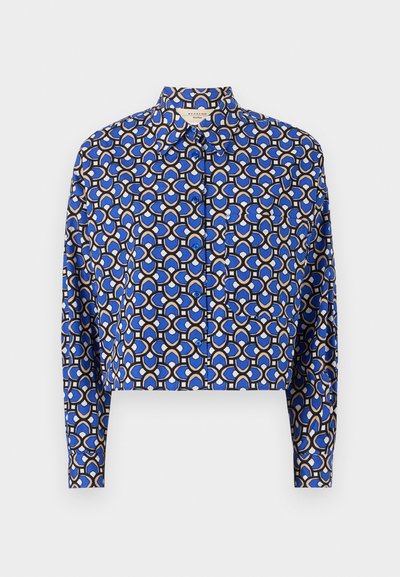 Cropped shirt in blue with a geometric print featuring interlocking circles in tan and black. It has a button-down front and long sleeves.