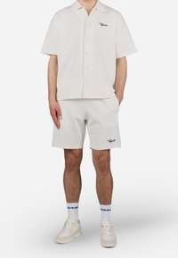 Korte mouwen, overhemd met knopen en bijpassende korte broek in een gestructureerde ivoorkleurige stof, met een ruitpatroon en contrasterende zwarte logo borduring.