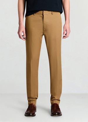 Maßgeschneiderte Hose aus einem hellbraunen Stoff. Sie zeichnet sich durch eine glatte Textur, einen geraden Schnitt und eine saubere Vorderseite ohne sichtbare Taschen aus. Kombiniert mit dunklen Schuhen.