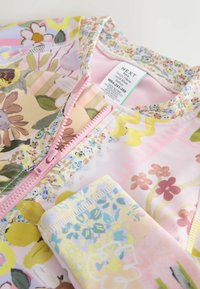 Barevné plavky s květinovým vzorem, růžovým zipem a lemováním. Měkká tkanina s různými květinovými motivy v pastelových barvách a texturách.