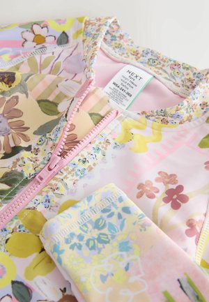 Farverigt badetøj med blomsterprint og en pink lynlås og kant. Blødt stof med forskellige blomsterdesigns, der har pastelfarver og teksturer.