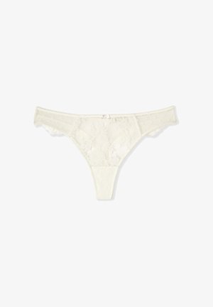 String en dentelle blanche avec motifs floraux, côtés en mesh, et petit nœud à l'avant sur fond blanc.