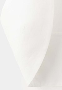 Gros plan d'un coin de tissu blanc avec un bord visible et une texture subtile sur un fond uni.