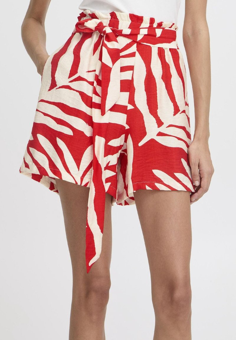 Shorts à motifs rouges et blancs avec une ceinture à nouer, présentant une coupe ample et un imprimé feuilles sur un tissu léger.