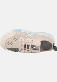Zapatilla deportiva de color rosa claro con parte superior de malla, acentos texturizados grises, detalles azules y logo negro, que presenta una suela de goma y cierre de cordones.