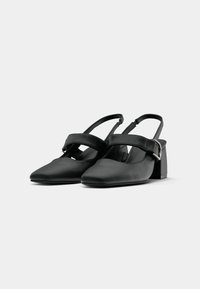 Juodos slingback aukštakulniai su smailiu nosiu, pagaminti iš lygaus odos, su plačia juosta per pėdą ir kvadratiniu blokiniu kulnu.