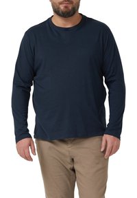 Maglietta a maniche lunghe blu navy scuro in morbido cotone, con scollo rotondo e vestibilità rilassata, abbinata a pantaloni beige.