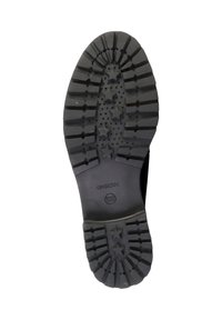Suela de zapato de goma negra con surcos profundos y patrones de estrellas. Presenta un borde liso y una marca en el centro. Diseño duradero para una mejor tracción.