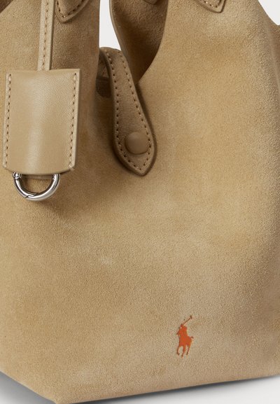 Τσάντα ώμου από καφέ σουέτ με ομαλή υφή, που διαθέτει μικρό πορτοκαλί λογότυπο, διπλές λαβές και δερμάτινο λουράκι με μεταλλικό κρίκο.