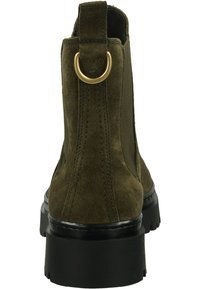 Green suede ankle boot with black chunky sole, elastic side panel, back loop, and gold metal ring detail.