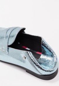 Mocassin bleu métallique avec une texture craquelée, doté d'un détail de porte-penny et d'un petit accent argenté. Doublure intérieure noire.