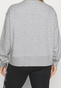 Grå sweatshirt med rund halsringning, långa ärmar och ribbad nederkant. Tyget verkar mjukt med en något texturerad yta. Enkelt design.