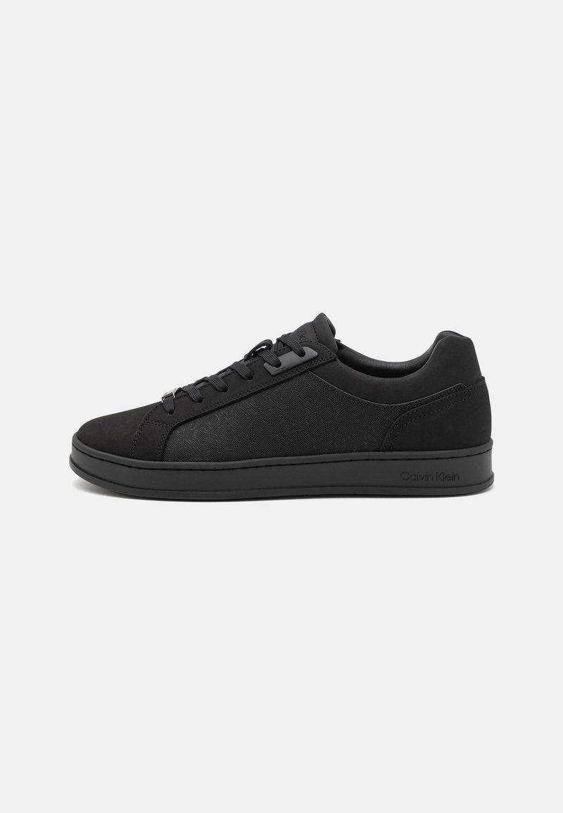 Adidași negri cu un model texturat, vârf rotunjit, talpă plată din cauciuc și șireturi negre. Prezintă un logo Calvin Klein pe lateral.