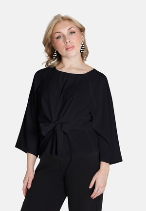 Black, lightweight top with a round neck, 3/4 sleeves, and a tie-front detail. Smooth texture, slightly loose fit, paired with black trousers.