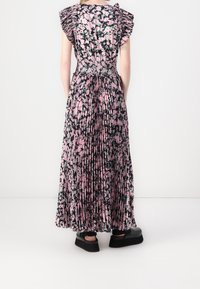 Maxi-mekko, jossa on vaaleanpunainen ja musta kukkakuosi, pleated-rakenne ja liehuvat hihat. Yhdistetty chunky-mustiin kenkiin.