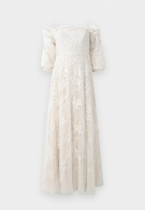 Robe longue décolletée en crème avec broderies florales texturées, manches bouffantes et une jupe fluide qui touche le sol.