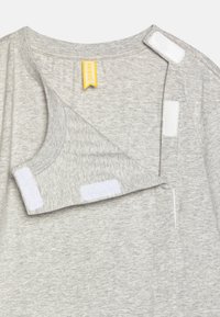 T-shirt en coton gris avec un col rond, doté de fermetures Velcro blanches au col et à l'épaule, étiquette marquée "FRIBOO" en jaune.
