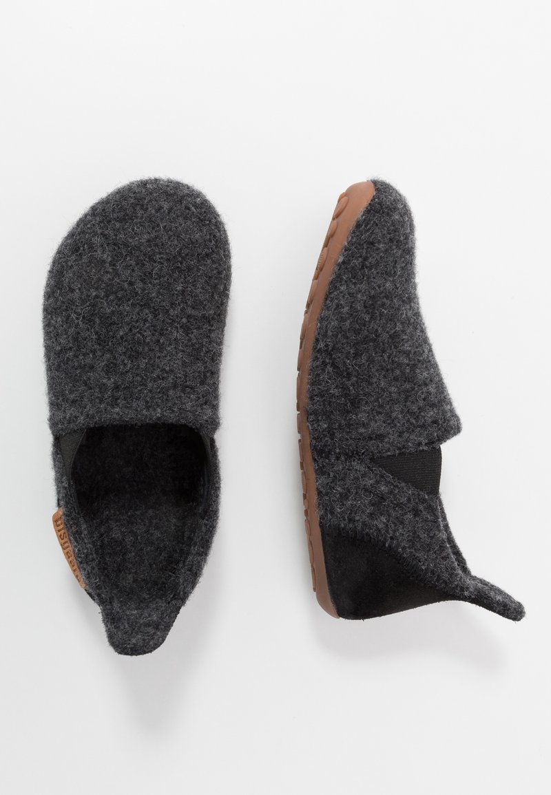 Chaussons d'intérieur en laine gris foncé, faciles à enfiler, avec des semelles en caoutchouc marron, dotés de bandes élastiques pour un enfilage facile et d'une petite languette en tissu au talon.