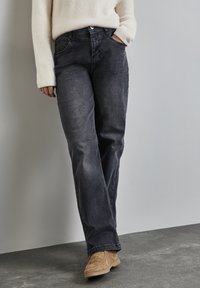 Jeans de mezclilla oscura con un diseño de pierna recta, que presentan un cierre frontal con botón, bolsillos laterales y una sutil textura deslavada.