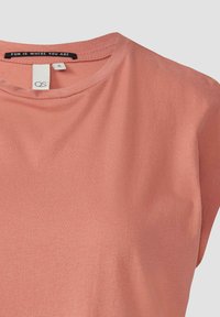 Jasno brzoskwiniowy T-shirt z okrągłym dekoltem i krótkimi rękawami. Wykonany z miękkiego materiału, z metką z napisem "ZABAWA JEST TAM, GDZIE TY JESTEŚ."