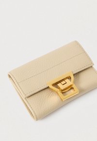 Κρεμ δερμάτινο πορτοφόλι με υφή και χρυσό ορθογώνιο κλείσιμο, τοποθετημένο σε ανοιχτό φόντο.