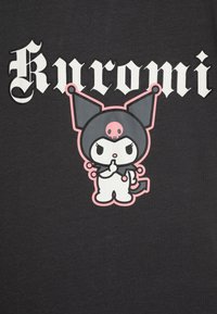 Črna bombažna majica s kratkimi rokavi, ki prikazuje risanega junaka s pink dodatki, špicastimi ušesi in lobanjo na glavi, z napisom "Kuromi" nad njim.